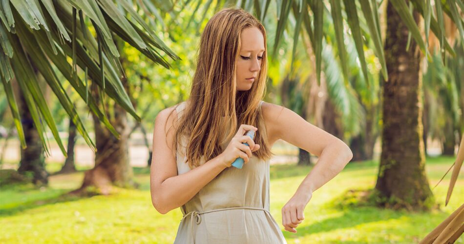 woman spraying insect repellent skin outdoor